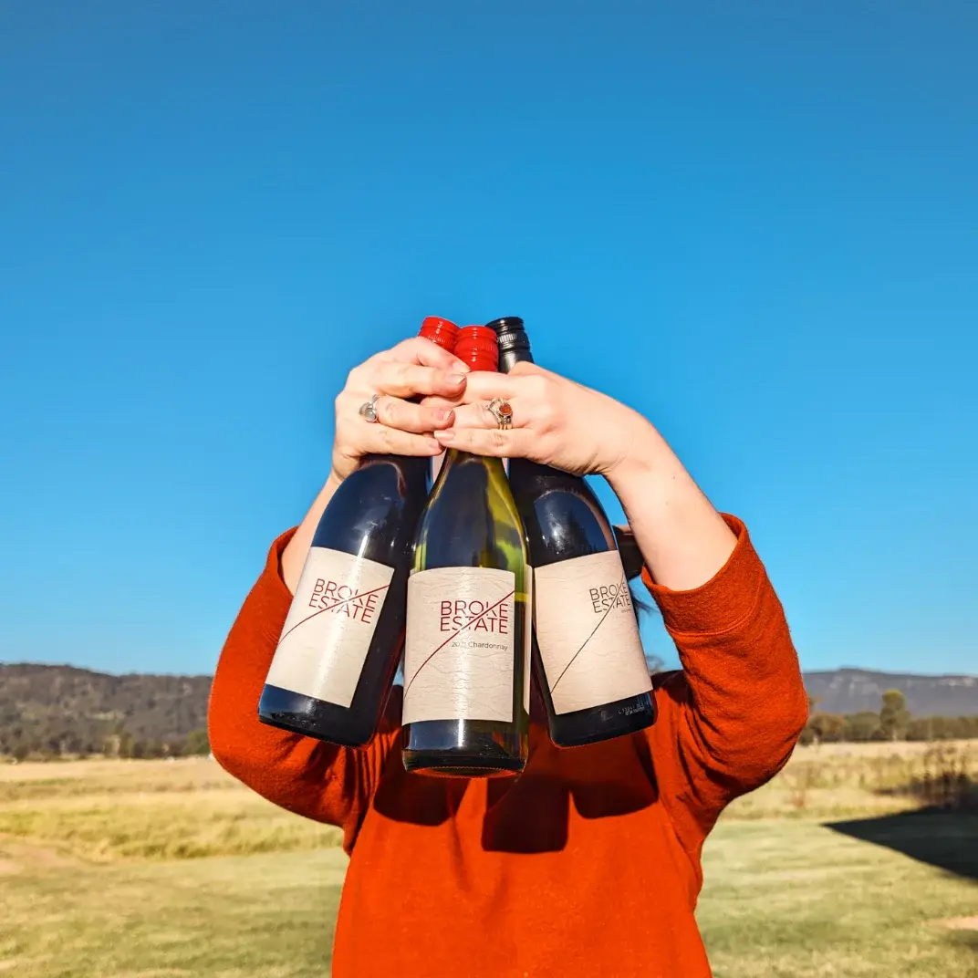 Broke Estate wine bottles held up in the paddock